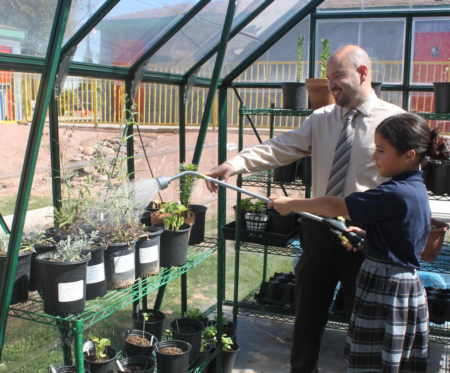 Principal Adam Sharp and a student watering plants.