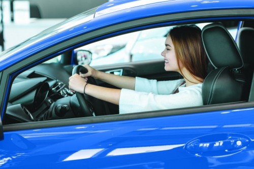 EA CAR 2 - Ready for road. Excited young woman smiling happily sitting in a car with her hands on the steering wheel ready to drive buying car dealership consumerism lifestyle driver insurance safety concept; Shutterstock ID 593599310 EA CAR 2