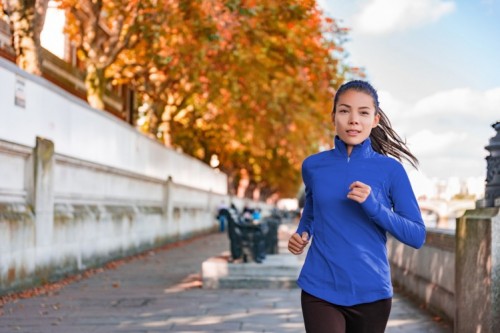 Jogging - Woman running in autumn fall outdoor city street. Female runner training outdoor in profile. Healthy lifestyle image of young Asian woman jogging outside. Fit ethnic Asian Caucasian fitness model. Jogging