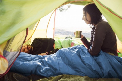 Summer holiday ideas - Two friend traveling and spending time in tent while drinking coffee in the morning. Happy people in camping. View from inside. Couple of travelers ; Shutterstock ID 630859922 Summer holiday ideas