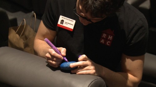 Third-year biochemistry student Josh Skektman paints rocks during Thursday's Kindness Rocks event at the Gateway Film Center