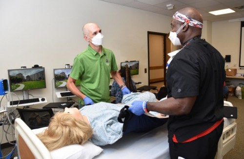 Crispin Del Nero and his colleague Rodney Adams demonstrate proper, safe patient turning technique using a life-like mannequin.