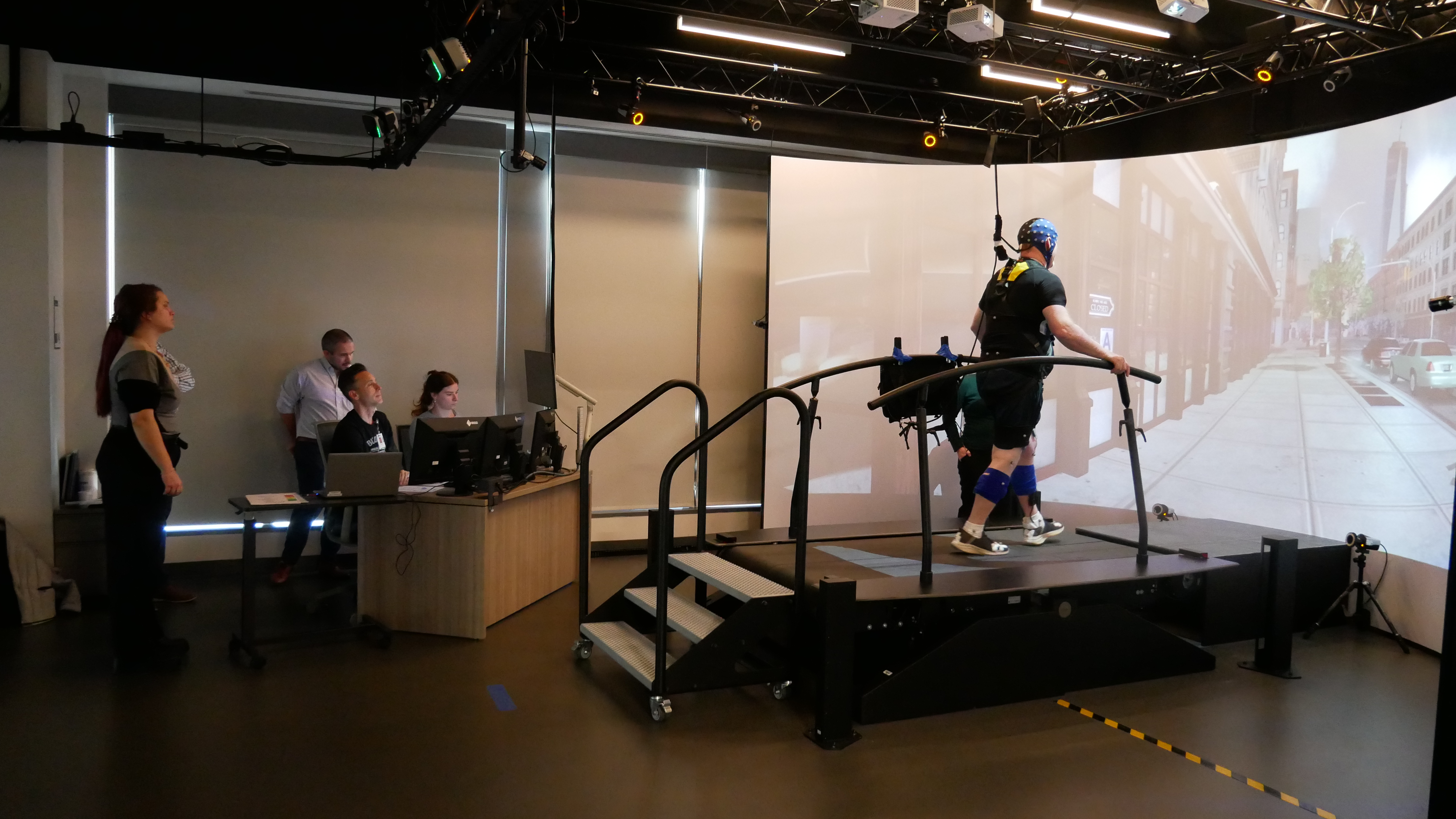 A research participant walks on a specialized treadmill, while researchers monitor his progress from nearby.