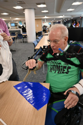 Tom Elkin practices lifting a fork to his mouth while using a mobile arm support.