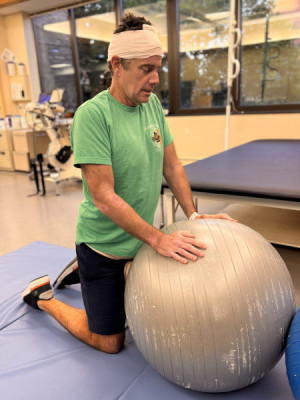 Jeff Millican prepares for shoulder exercises with an exercise ball.