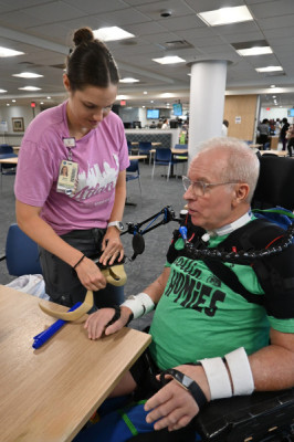 Occupational therapist Marie Alexander helps Tom Elkin get set up with his mobile arm support.