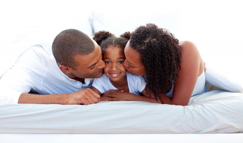 Cheerful Parents Kissing Their Daughter