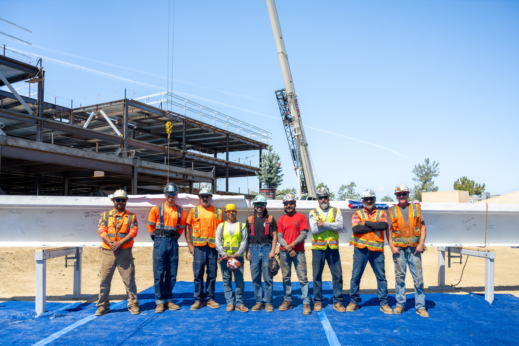 Construction workers stand in front of the topping-out beam. Photo by ...