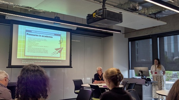 A presenter at the ALN conference delivering a talk related to pressures in academia