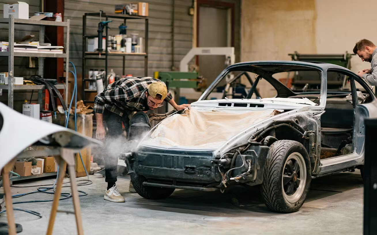 Stripped-back_Porsche_911_in_a_car_repair_shop_with_men_working_on_it