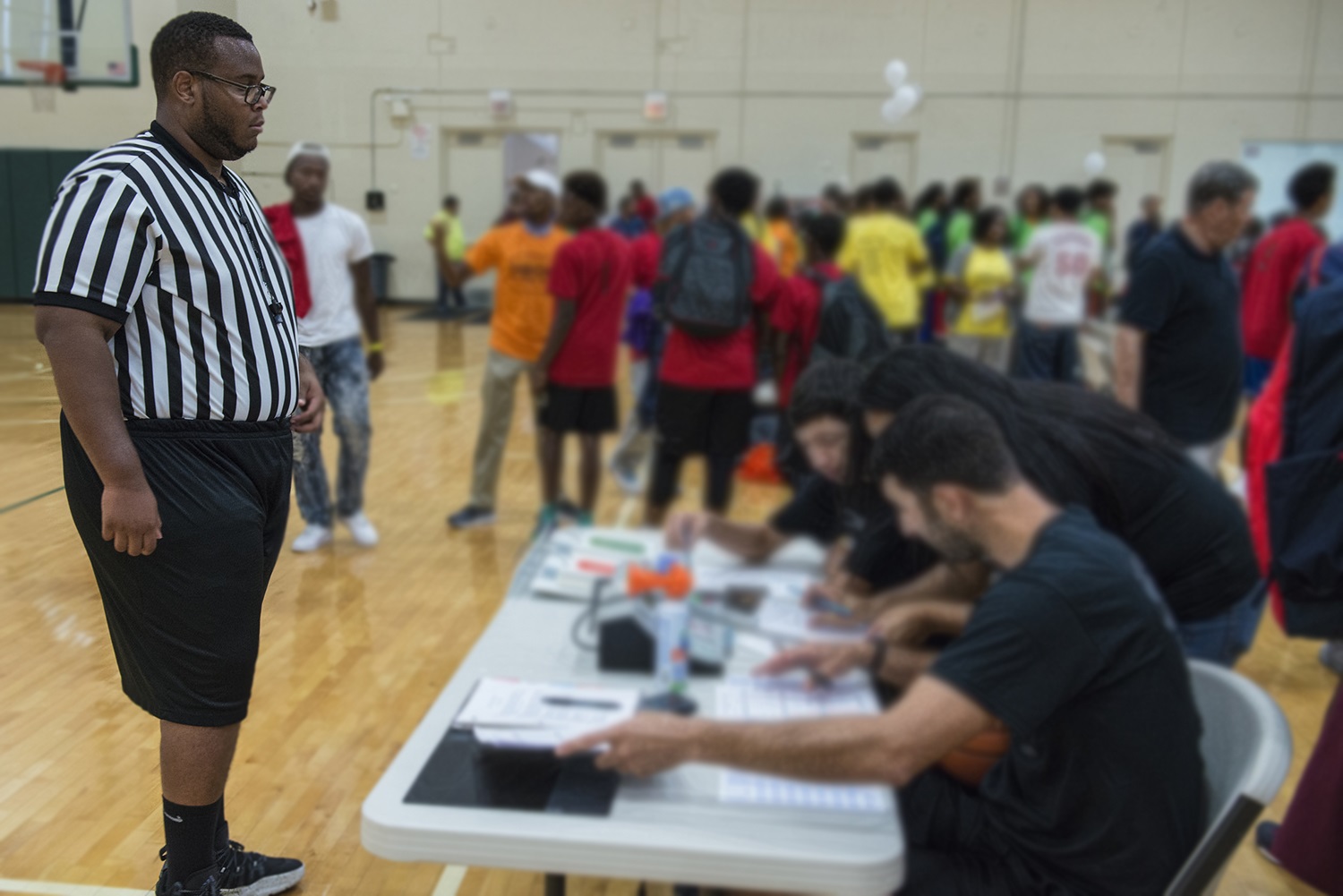 Andrell Bryant takes time out from the basketball game to talk with volunteers sitting at a table in the gym.