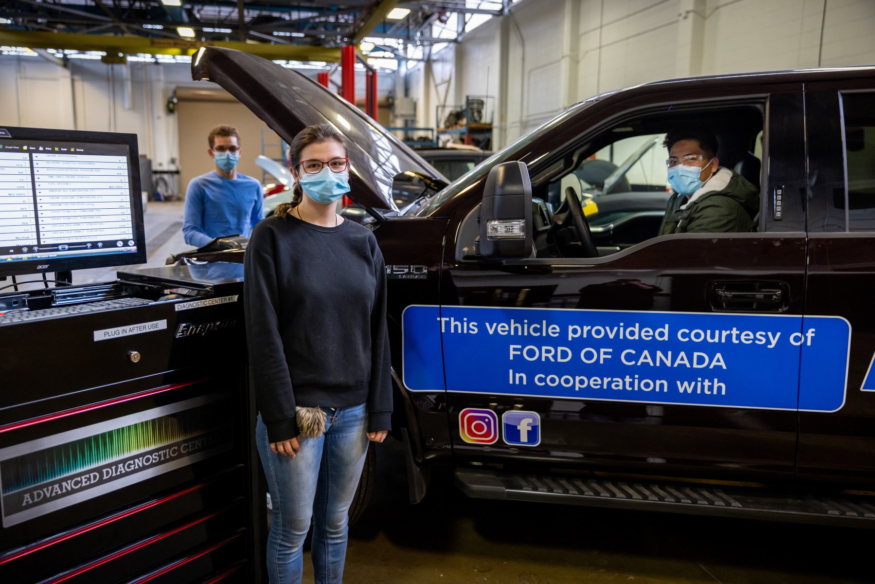 students pose by a Ford truck with a donation message