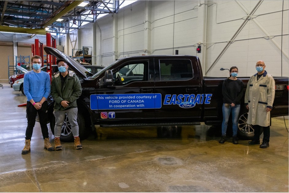students pose with Professor Bob Brown by a donated truck