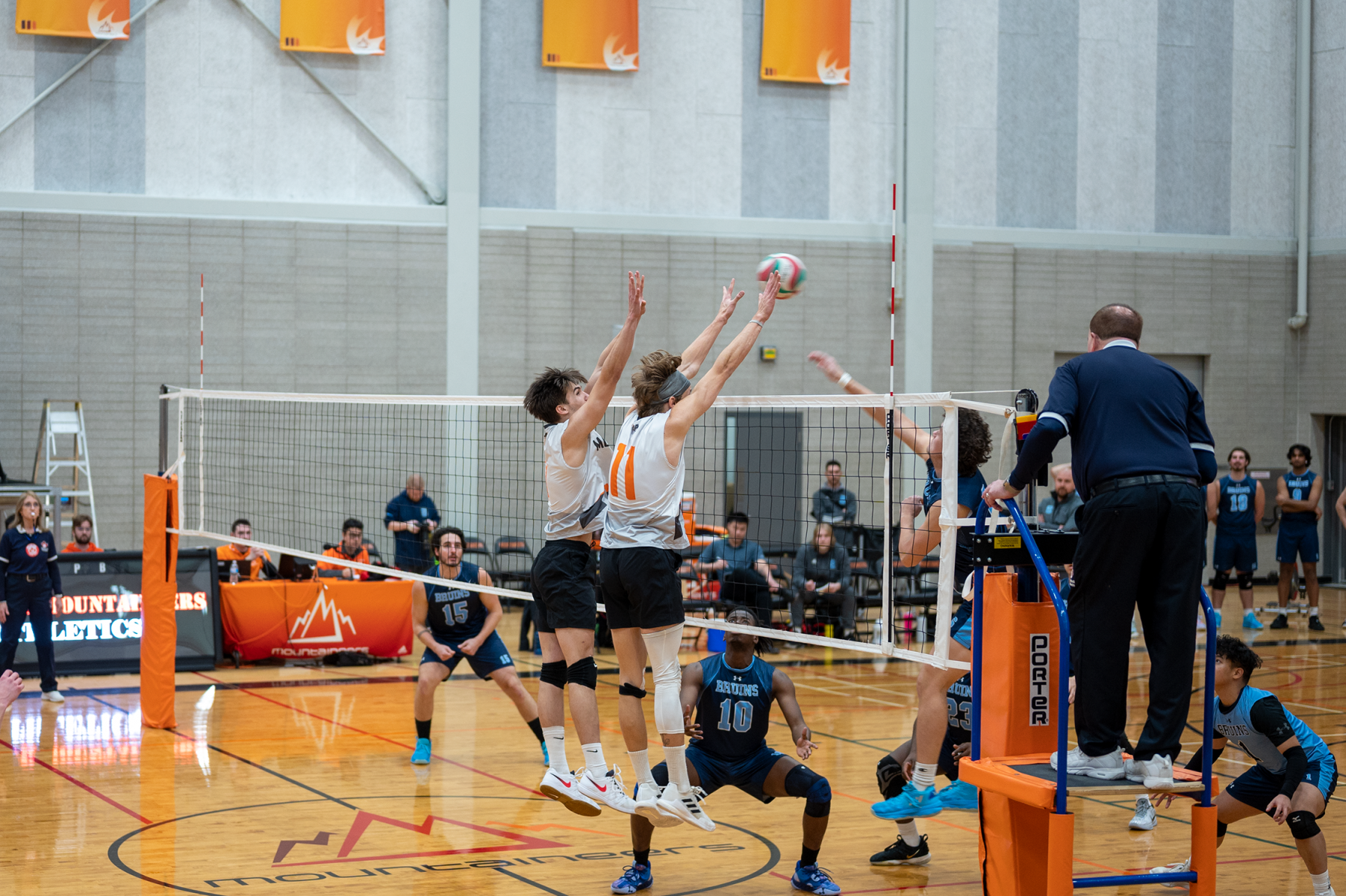 Women's volleyball players blocking a spike
