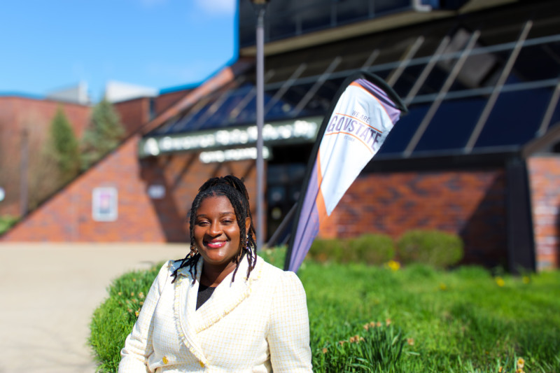 A smiling woman in a cream blazer standing in front of Governors State University