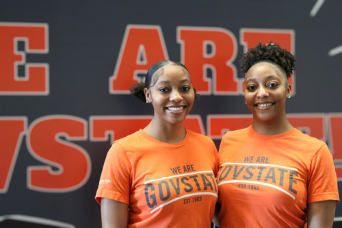 Two smiling twin sisters wearing Governors State University t shirts