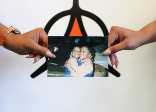 Picture of two women's hands holding up a childhood photo together