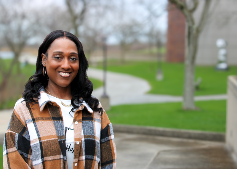 A smiling woman standing outside on the Governors State University campus