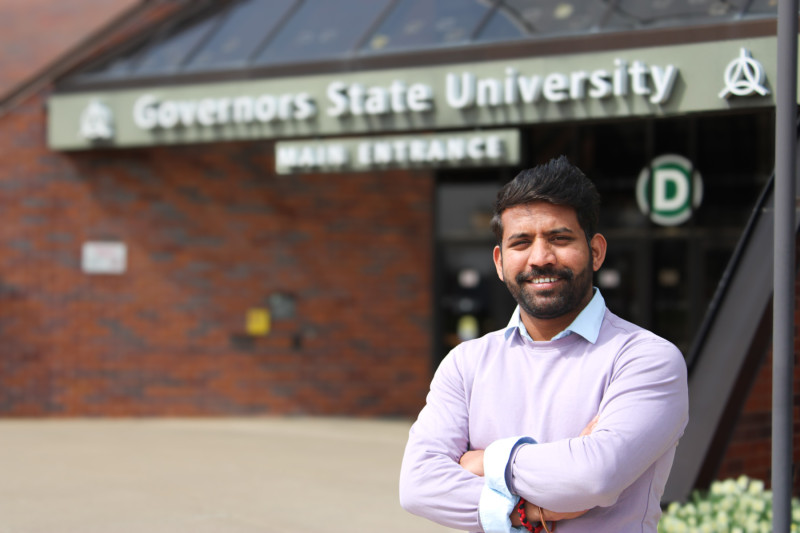 A smiling man standing in front of Governors State University