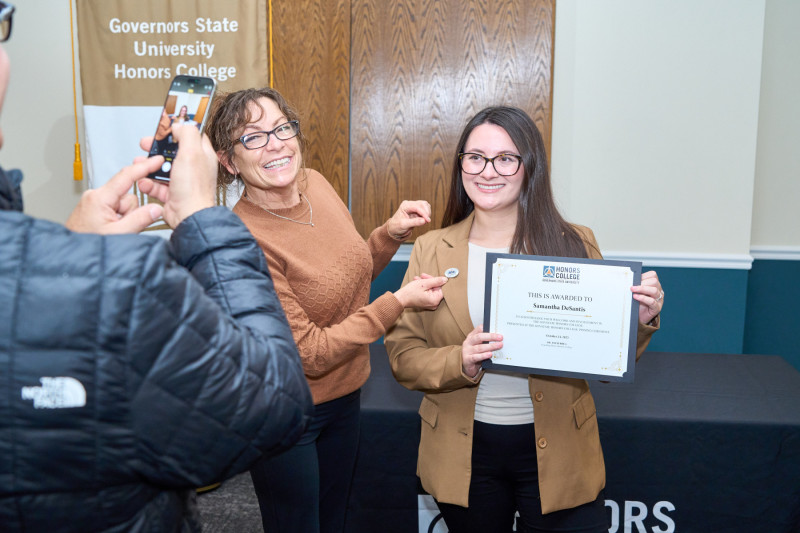 A Governors State University honors student receiving a pin at a pinning ceremony