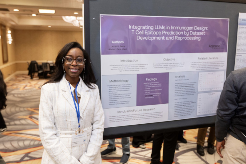 A woman smiling while standing by her research presentation board