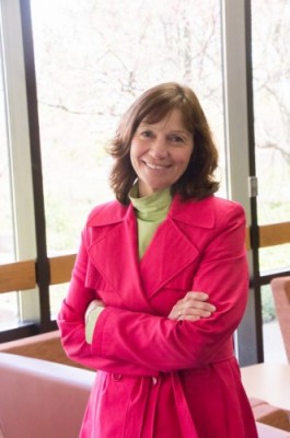 Professor Klomes stands near a window smiling warmly