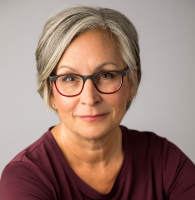 Headshot of a smiling woman wearing maroon glasses and a maroon shirt