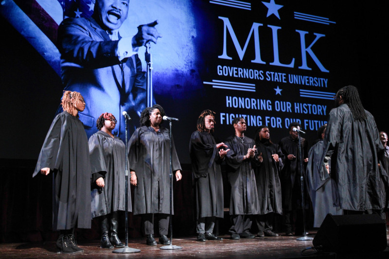 A gospel choir in black robes performing on stage