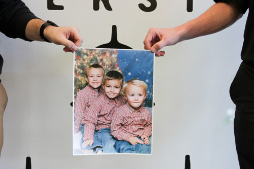 Picture of two men's hands holding up a childhood photo together