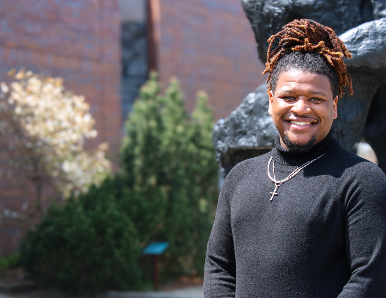 A smiling man standing in front of a sculpture at Governors State University