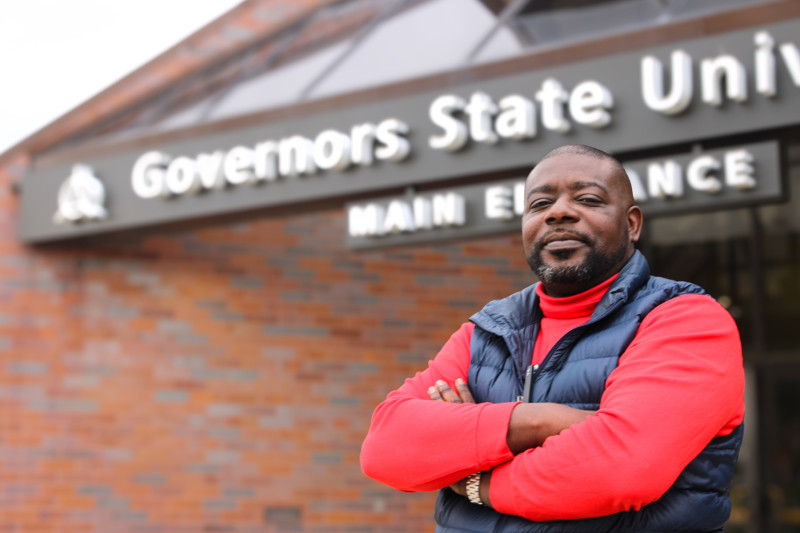A man crossing his arms standing in front of Governors State University