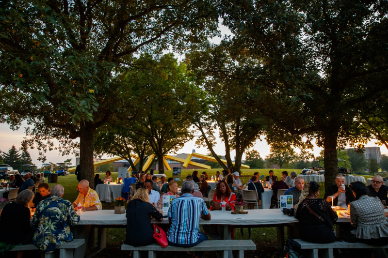 People sitting at tables outside for a reception event at the Nathan Manilow Sculpture Park at Governors State University