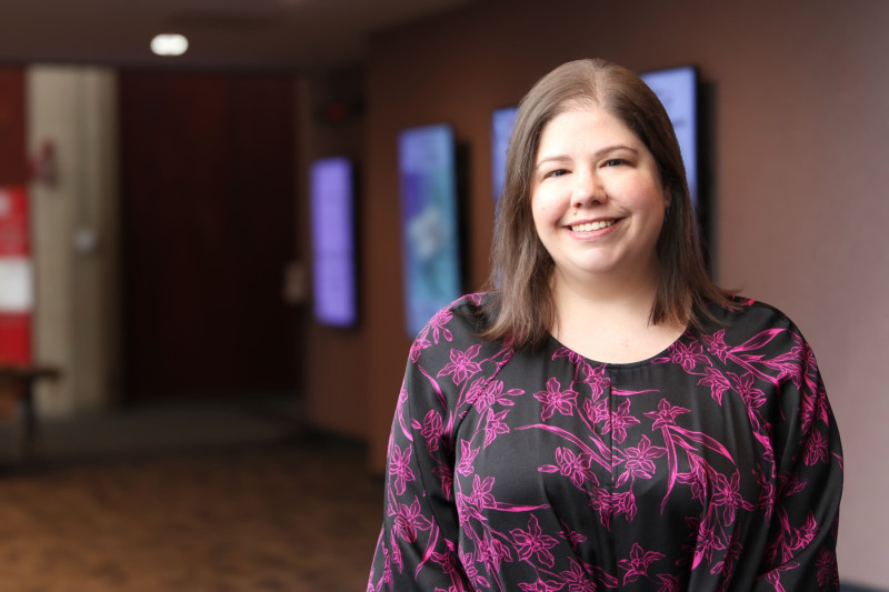 A smiling woman standing in the hallway of the Performing Arts Center at Governors State University