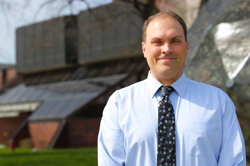 A smiling man standing outside Governors State University