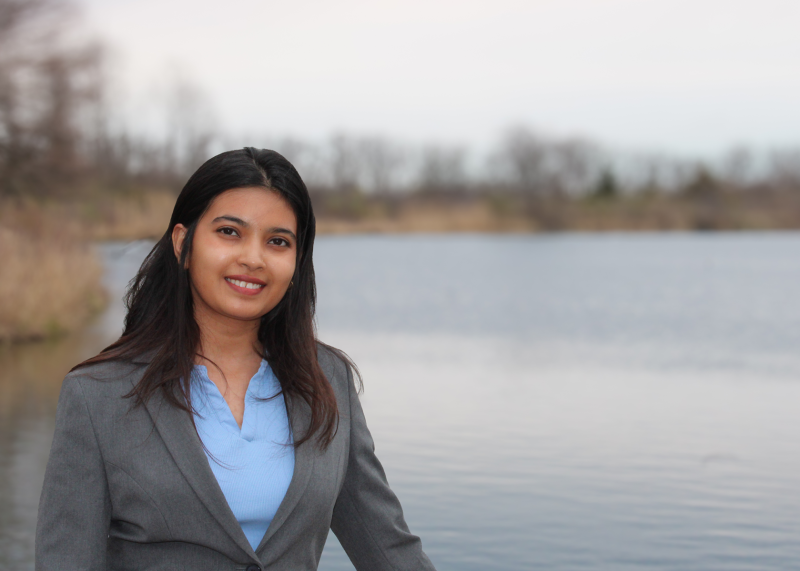 A smiling woman standing by a lake on the Governors State University campus
