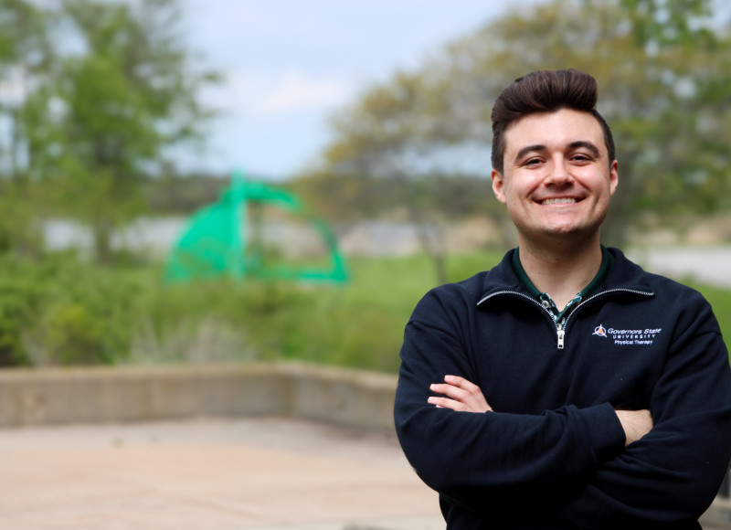 A smiling Governors State University student wearing his physical therapy jacket