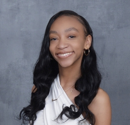 Headshot of a smiling women wearing a white off the shoulder shirt