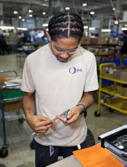 A man inspecting a metal piece in a manufacturing plant