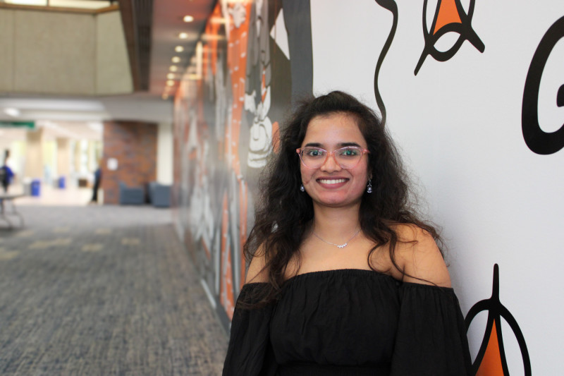 A smiling woman standing in front of a mural at Governors State University