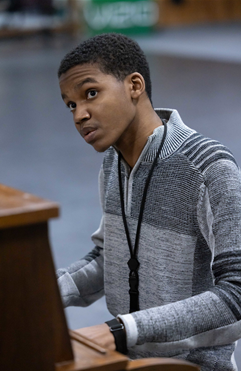 A man Julian Johnson playing a brown piano