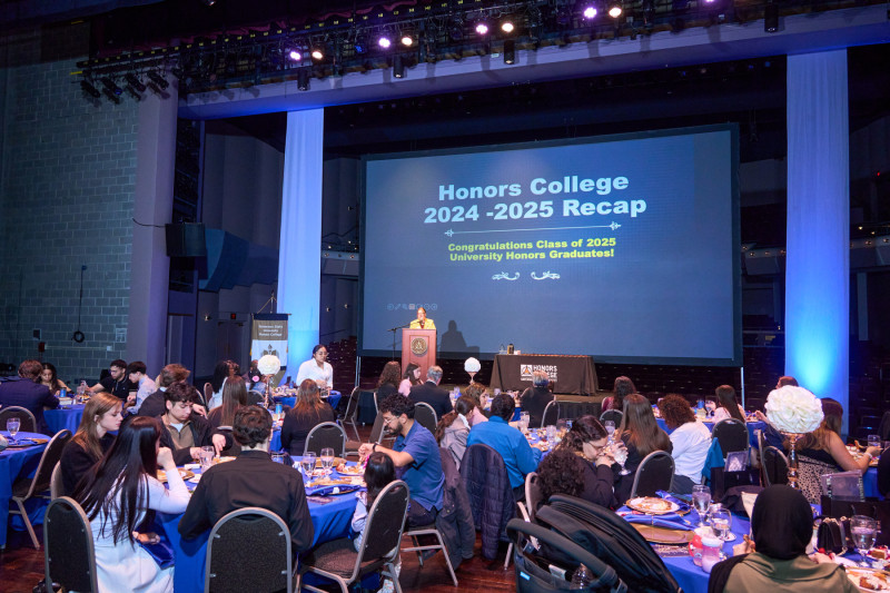 A room of people sitting at royal blue clothed tables for the 2025 Governors State University Honors Banquet