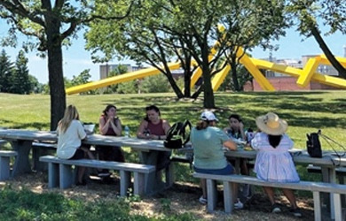 People sitting at a stone picnic table eating lunch on Governors State University campus