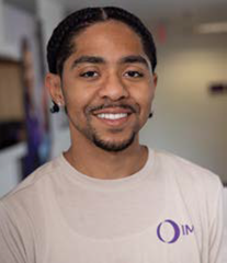 Headshot of a smiling man wearing a beige t shirt