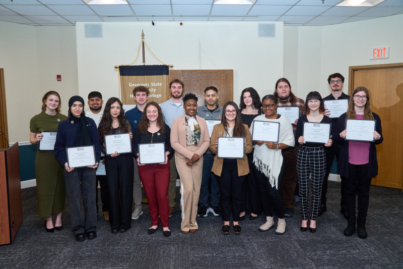 A group of Governors State University Honors students standing and smiling while holding their honors certificates