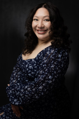 Headshot of a smiling woman Victoria Gomez wearing a navy floral dress