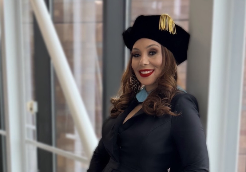 Portrait photo of a smiling woman wearing black with a graduation doctoral hat