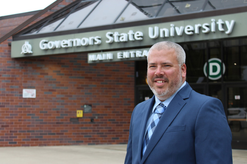 A smiling man standing in front of Governors State University