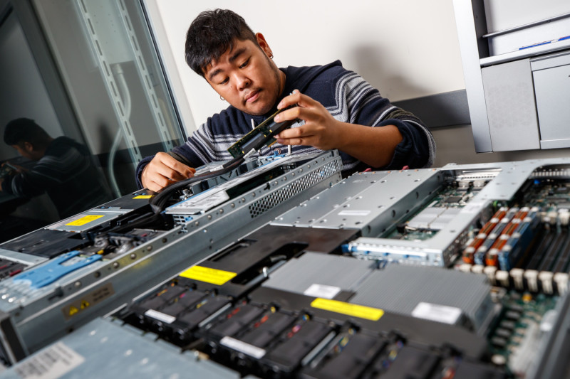 A student working on rebuilding a computer system with wires and panels