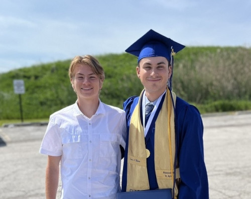 A smiling man in blue graduation gown with his brother