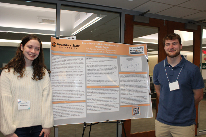 Two Governors State University students standing and smiling with their project poster